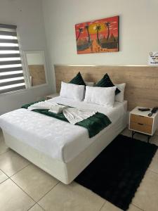 a bedroom with a large bed with white sheets and greens at Chirute guest lodge in Randfontein