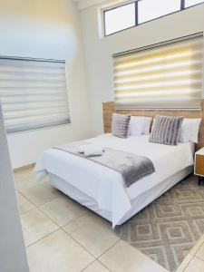a white bedroom with a large white bed with pillows at Chirute guest lodge in Randfontein