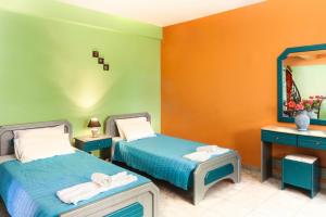 a bedroom with two beds and a mirror at Haroula Apartments in Sidari