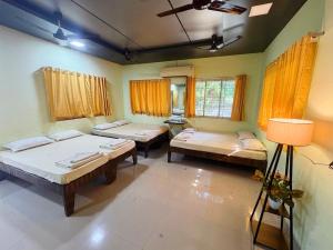 a room with three beds and a lamp in it at Matoshree Green Garden Resort in Badlapur