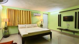 a bedroom with a bed with green walls and a tv at Matoshree Green Garden Resort in Badlapur