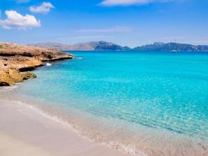 a beach with blue water and mountains in the background at Fonda Llabres Boutique in Alcudia