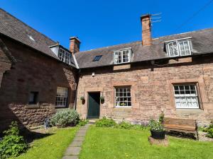 an old brick house with a bench in the yard at Gamekeepers Cottage in Chillingham