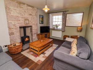 a living room with a couch and a fireplace at Gamekeepers Cottage in Chillingham