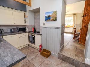 a kitchen with white cabinets and a tile floor at Gamekeepers Cottage in Chillingham