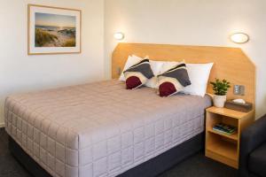 a bedroom with a large bed with two pillows at Southern Cross Motor Inn in Narrabri