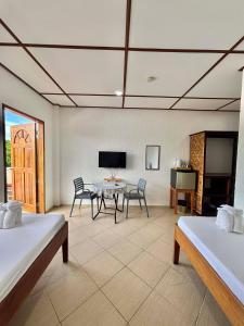 a room with two beds and a table and chairs at Sunville Hotel and Restaurant in Panglao Island
