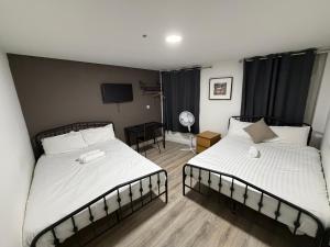 a bedroom with two beds and a television in it at TBH Hotel in Barking