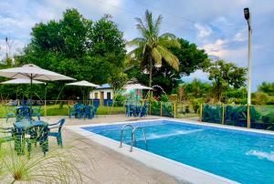 a swimming pool with tables and chairs next to at Finca Hotel La Herencia Cafetera in Montenegro