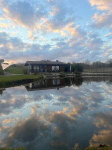 ein Haus mit Spiegelung in einem See unter bewölktem Himmel in der Unterkunft Vila Trakai in Trakai