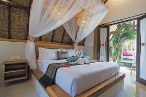 a bedroom with a white bed with curtains at Gili Air Bungalows in Gili Islands +42 photos
