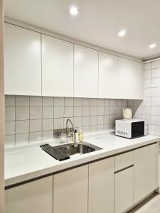 a white kitchen with a sink and a microwave at Coco Villa Sinsa in Seoul