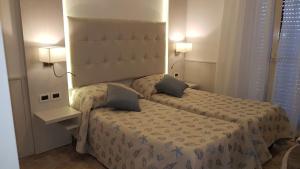 una camera d'albergo con due letti e due lampade di Hotel Bella Riviera Lungomare a Viareggio
