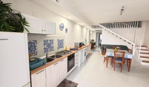 a kitchen with white cabinets and a table with chairs at On The Beach SORRENTO in Massa Lubrense