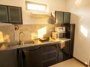 a small kitchen with a sink and a microwave at La Nuit Étoilée , Restez plus, payez moins ! in La Gaulette