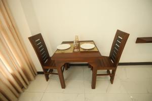 a wooden table and two chairs with plates on it at Ruish City Kandy in Kandy +11 photos