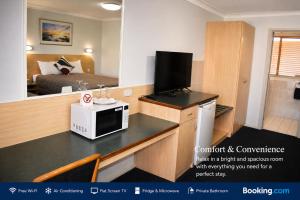 a room with a kitchen with a microwave and a bed at Southern Cross Motor Inn in Narrabri +2 photos