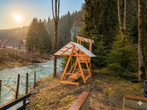 a wooden structure sitting on the side of a river at Refugiul Apusenilor in Scărişoara