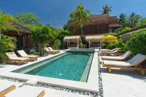 a pool at a resort with chaise lounge chairs at Gili Air Bungalows in Gili Islands