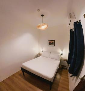 a small bedroom with a white bed and a lamp at Puy-An, A Nomad Hostel in Moalboal