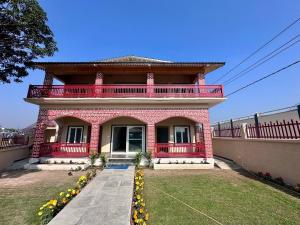 a red brick house with a balcony on top at Corbett Krishna Inn in Belparāo
