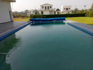 a pool of water with blue infront of a house at Corbett Krishna Inn in Belparāo