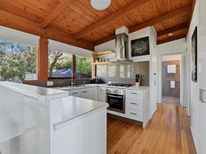 a kitchen with white cabinets and a wooden ceiling at Prom Coast Oasis - Sandy Point in Sandy Point +22 photos