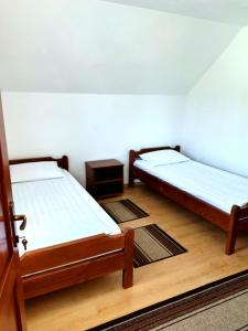 two beds in a room with wooden floors at Akácpatak Vendégház in Lupeni