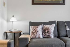 a gray couch with two cats pillows on it at Lantern 22 - Balcony in Thredbo