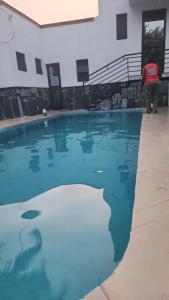 a man standing next to a swimming pool at APARTMENT 01 Meadowbrook Home Stade in Kasaayi +4 photos