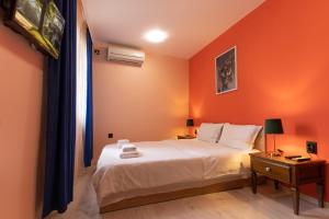 a bedroom with a bed with an orange wall at Aleko Apartments City Center in Veliko Tŭrnovo