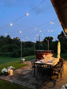 eine Terrasse mit Tisch, Stühlen und Beleuchtung in der Unterkunft Vila Trakai in Trakai