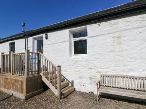 a white building with a staircase and a bench at Gun Powder Cottage in Tighnabruaich