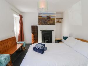 a bedroom with a white bed and a fireplace at Gun Powder Cottage in Tighnabruaich