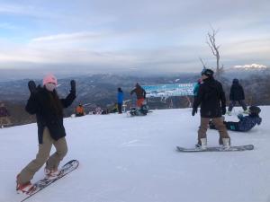 a group of people on snowboards on a ski slope at Hakuba Inn Bloom in Hakuba