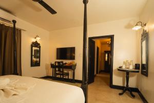 a bedroom with a bed and a table and a mirror at Fort Tiracol Goa in Arambol
