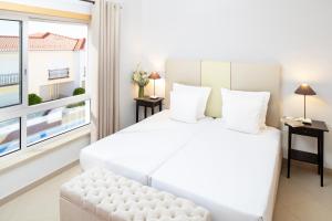 une chambre avec un grand lit blanc et une fenêtre dans l'établissement The Village – Praia D’El Rey Golf & Beach Resort, à Casal da Lagoa Seca