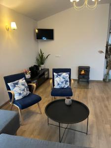ein Wohnzimmer mit zwei Stühlen, einem Tisch und einem Kamin in der Unterkunft Vila Trakai in Trakai