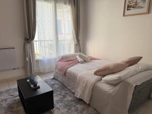 a bedroom with a bed with a table and a window at Bienvenue au Nid Rosé in Montereau-Fault-Yonne