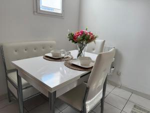 a white dining room table with a vase of flowers on it at Bienvenue au Nid Rosé in Montereau-Fault-Yonne