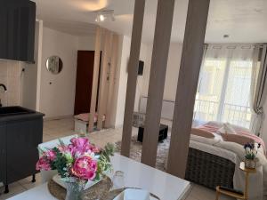 a living room with a bed and a table with flowers at Bienvenue au Nid Rosé in Montereau-Fault-Yonne
