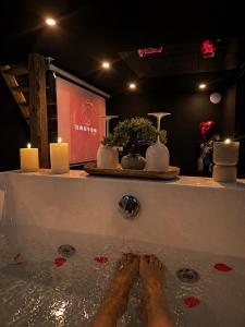 a person standing in a bath tub with candles at Love Room balnéo double & sauna Privés - Nuit d'exception in Briord