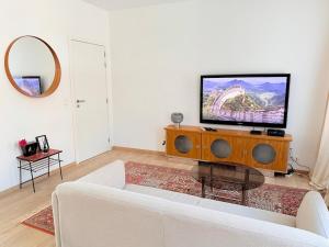 a living room with a white couch and a flat screen tv at TRIPLEX 2 chambres Cosy à MONS in Mons