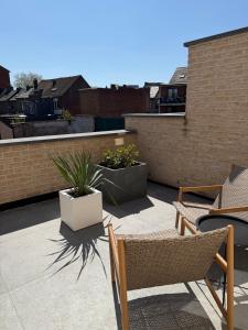 a patio with chairs and potted plants on a building at TRIPLEX 2 chambres Cosy à MONS in Mons