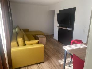 a living room with a yellow couch and a television at Die Perle an der Wutach in Lauchringen