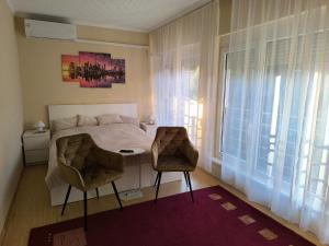 a bedroom with a bed and a table and two chairs at FAVORIT CENTRUM Apartman in Kaposvár