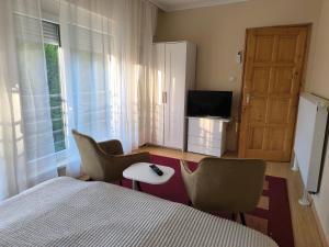 a bedroom with a bed and two chairs and a television at FAVORIT CENTRUM Apartman in Kaposvár