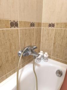 a bath tub with a faucet and two cups on it at FAVORIT CENTRUM Apartman in Kaposvár