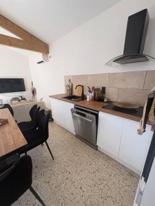 a kitchen with white cabinets and a table and a stove at La maison de Petit Pierre in Vauvert