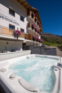 une baignoire jacuzzi en face d'un bâtiment dans l'établissement Residence Weisskugel Langtaufers Südtirol, à Melago